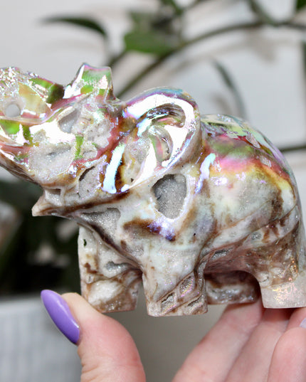 This Aura Quartz Elephant Carving features a charming hand-carved design enhanced with a brilliant rainbow electroplated finish. Made from natural quartz and treated to produce a luminous, color-shifting surface, this figurine blends natural beauty with a playful, eye-catching twist.