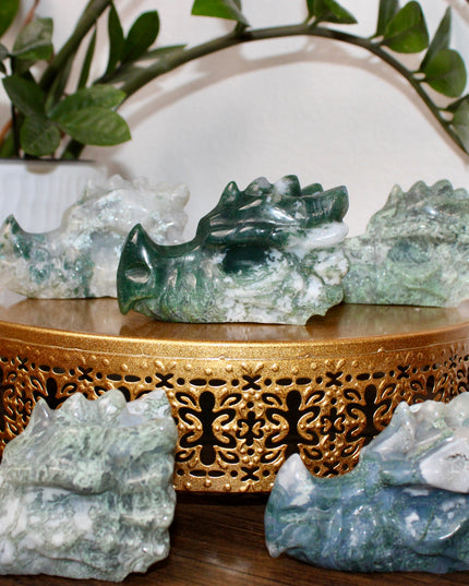 Bring a sense of majestic artistry and natural wonder into your space with this hand‑carved moss agate dragon skull. Sculpted from a single piece of genuine moss agate celebrated for its swirling green “moss-like” inclusions set against milky chalcedony, each piece showcases its own unique, earthy landscape