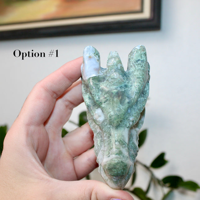 Bring a sense of majestic artistry and natural wonder into your space with this hand‑carved moss agate dragon skull. Sculpted from a single piece of genuine moss agate celebrated for its swirling green “moss-like” inclusions set against milky chalcedony, each piece showcases its own unique, earthy landscape