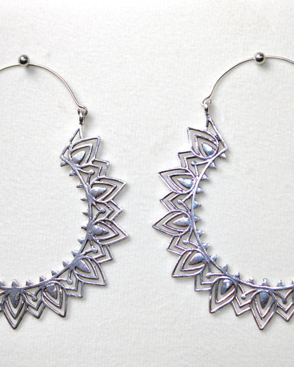 Silver hoop gauge earring with intricate Indian mandala design held in a hand against a plain background