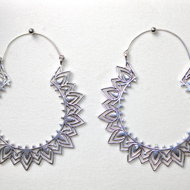 Silver hoop gauge earring with intricate Indian mandala design held in a hand against a plain background