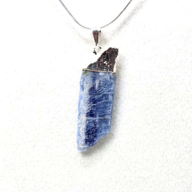 This handmade Blue Kyanite necklace features a raw, unpolished stone that highlights the natural striations and shimmer of the mineral. Set on a sleek silver-tone chain, the pendant offers a minimalist, earthy aesthetic perfect for everyday wear or adding a unique touch to layered outfits.