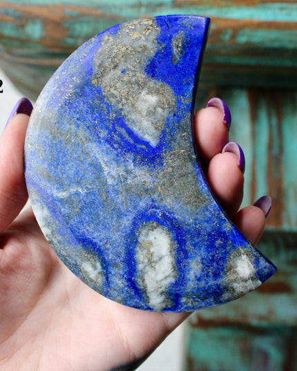 Crescent-shaped blue lapis held by a hand with text indicating size and option.