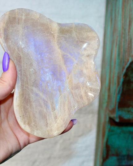 This Moonstone Bowl is carved from natural stone and polished to reveal stunning blue flash across its surface. Its compact size and elegant shine make it both functional and decorative ideal for adding a touch of iridescence to any space