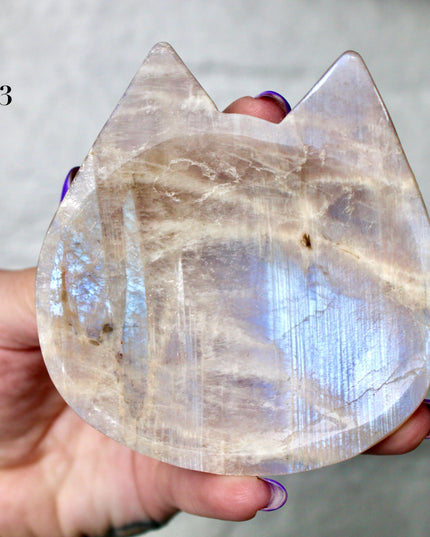 This Moonstone Bowl is carved from natural stone and polished to reveal stunning blue flash across its surface. Its compact size and elegant shine make it both functional and decorative ideal for adding a touch of iridescence to any space