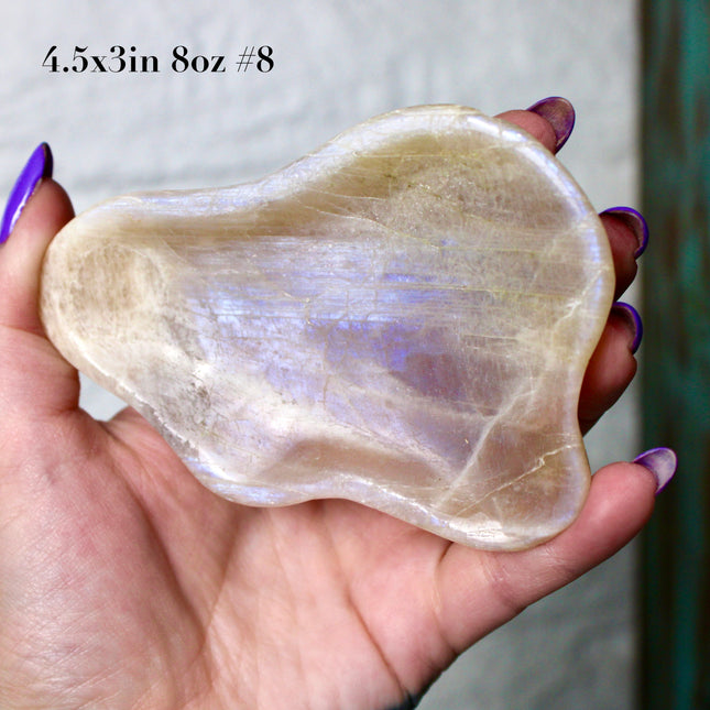 This Moonstone Bowl is carved from natural stone and polished to reveal stunning blue flash across its surface. Its compact size and elegant shine make it both functional and decorative ideal for adding a touch of iridescence to any space