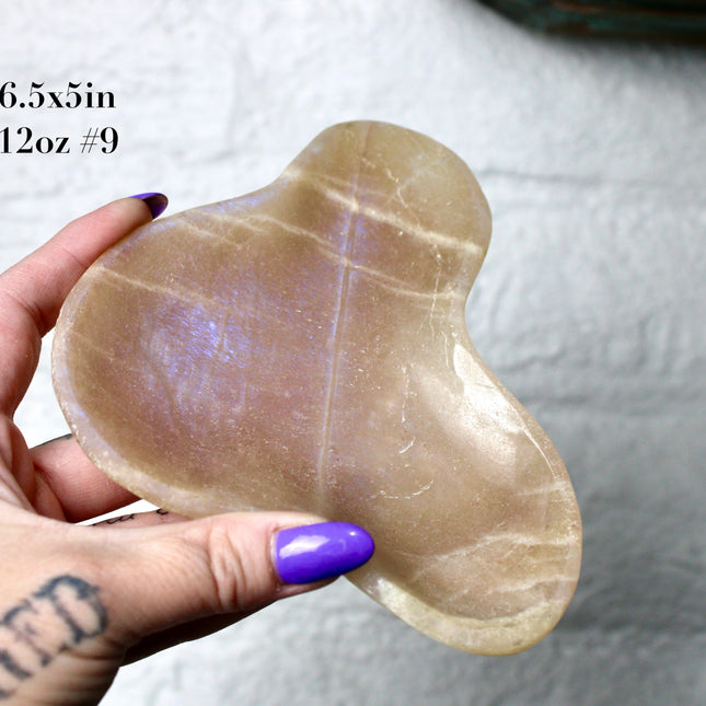This Moonstone Bowl is carved from natural stone and polished to reveal stunning blue flash across its surface. Its compact size and elegant shine make it both functional and decorative ideal for adding a touch of iridescence to any space