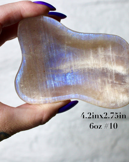 This Moonstone Bowl is carved from natural stone and polished to reveal stunning blue flash across its surface. Its compact size and elegant shine make it both functional and decorative ideal for adding a touch of iridescence to any space