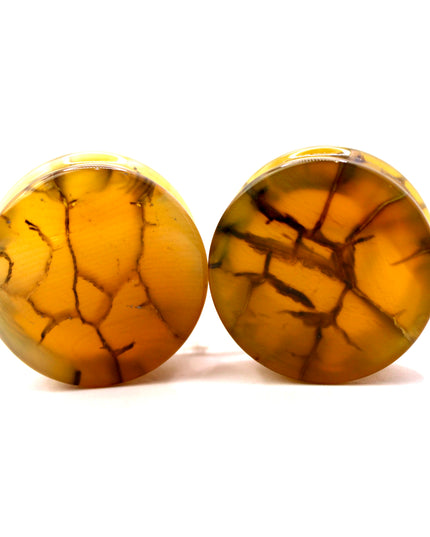These Yellow and Black Dragon Vein Agate Plugs offer a striking blend of color and texture, featuring polished surfaces and natural-looking crackle patterns. Designed in a secure double flare style, they’re a bold and stylish option for stretched ears.