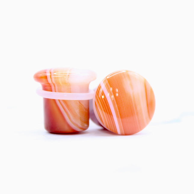 These single flare plugs are carved from genuine Carnelian Agate, showcasing warm, fiery hues and occasional natural banding or translucent zones. Hand-polished to a sleek finish, each plug is smooth and comfortable for everyday wear.