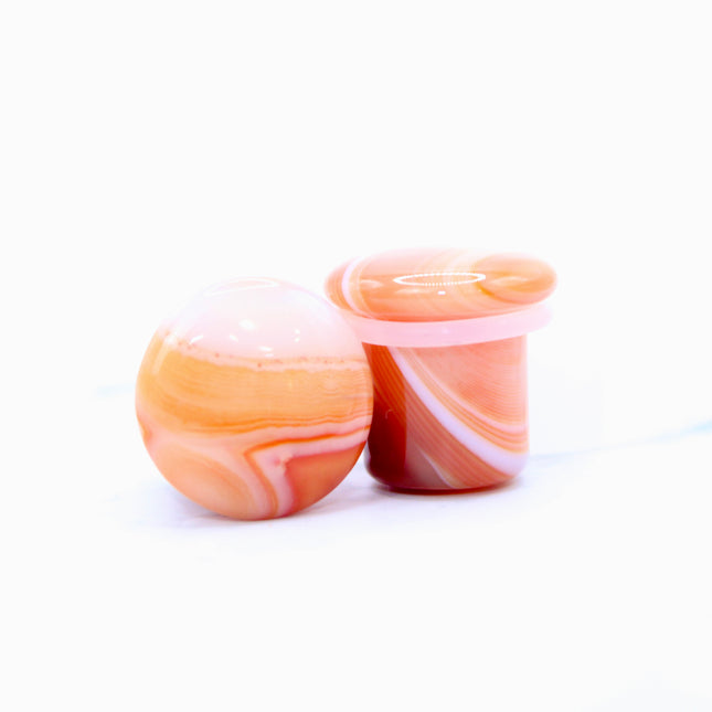 These single flare plugs are carved from genuine Carnelian Agate, showcasing warm, fiery hues and occasional natural banding or translucent zones. Hand-polished to a sleek finish, each plug is smooth and comfortable for everyday wear.