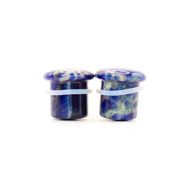 Pair of blue and white sodalite round plugs on a white background