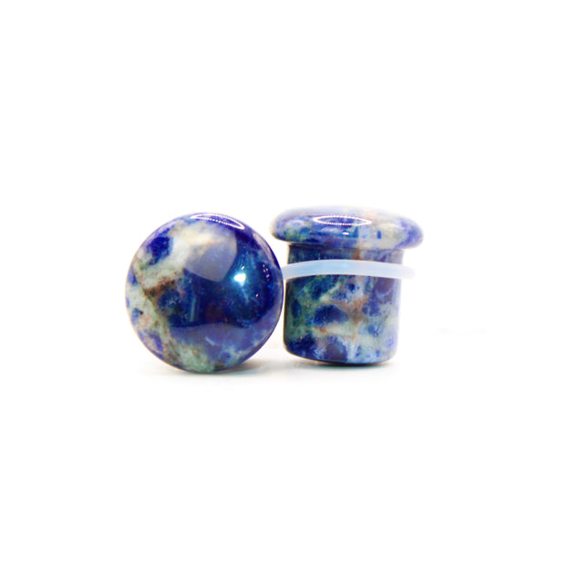 Pair of blue and white sodalite round plugs on a white background