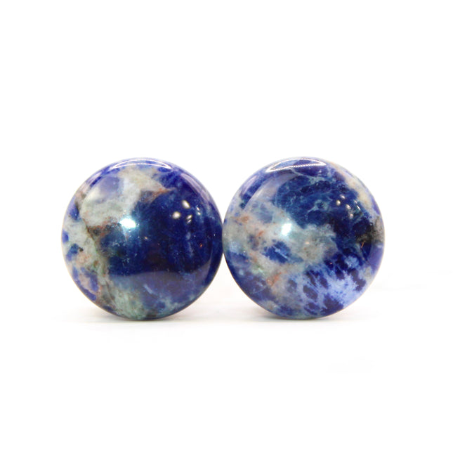 Pair of blue and white sodalite round plugs on a white background