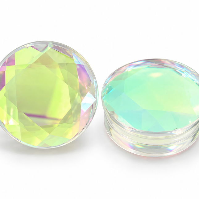 Two round, faceted clear glass plugs with an iridescent, holographic finish, one standing vertically and the other lying horizontally, on a white background.