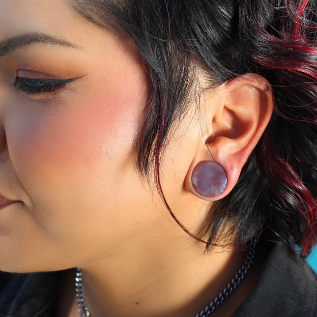 A beautifully varied pair of Rainbow Indian Agate Plugs rests on a natural-toned background, each plug showcasing its own unique mix of earthy colors. From deep forest green and mossy olive to warm rust, cream, and occasional hints of burgundy or gray, the natural banding and marbling of the stone give these plugs a one-of-a-kind character. The polished surface brings out the rich tones and subtle textures of the agate. Shaped with a comfortable, secure double flare, these plugs are perfect for those who ap