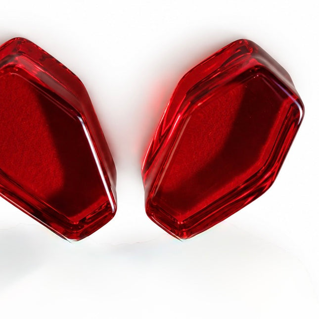 A pair of red translucent hexagonal plastic pieces, likely replacement lenses or covers, shown on a clean white background.
