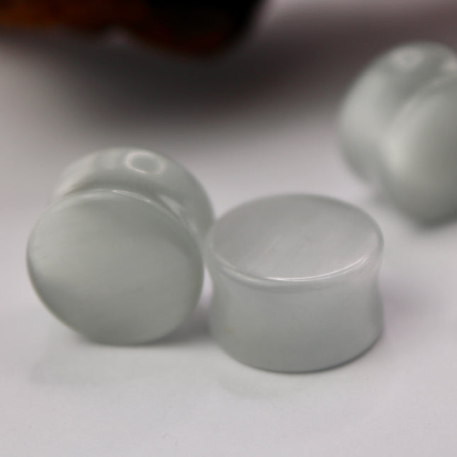 A sleek and shimmering pair of Silver Cat's Eye glass plugs, crafted with precision and finished to a flawless polish. These double flare plugs feature a metallic silver sheen with a mesmerizing “cat’s eye” effect—an optical reflection that shifts with the light, creating a glowing, fiber-optic-like line across the center. Smooth and lightweight, each plug offers a comfortable, secure fit ideal for daily wear.