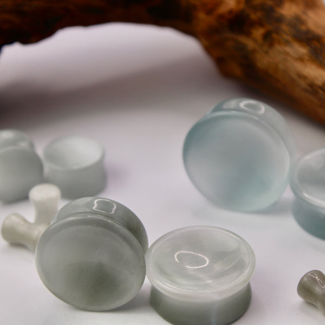 A sleek and shimmering pair of Silver Cat's Eye glass plugs, crafted with precision and finished to a flawless polish. These double flare plugs feature a metallic silver sheen with a mesmerizing “cat’s eye” effect—an optical reflection that shifts with the light, creating a glowing, fiber-optic-like line across the center. Smooth and lightweight, each plug offers a comfortable, secure fit ideal for daily wear.