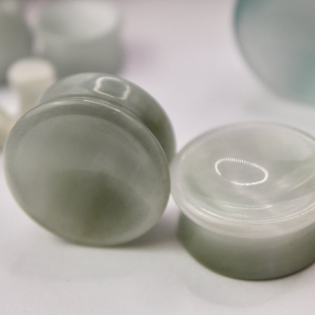 A sleek and shimmering pair of Silver Cat's Eye glass plugs, crafted with precision and finished to a flawless polish. These double flare plugs feature a metallic silver sheen with a mesmerizing “cat’s eye” effect—an optical reflection that shifts with the light, creating a glowing, fiber-optic-like line across the center. Smooth and lightweight, each plug offers a comfortable, secure fit ideal for daily wear.