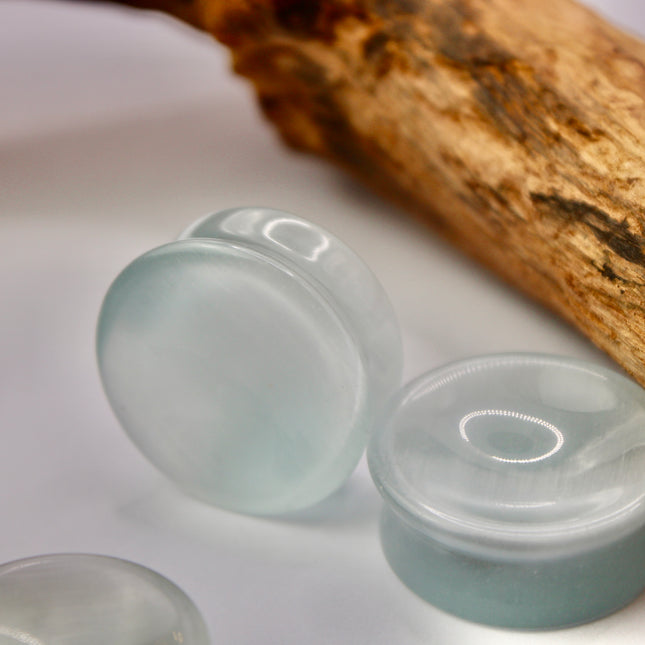 A sleek and shimmering pair of Silver Cat's Eye glass plugs, crafted with precision and finished to a flawless polish. These double flare plugs feature a metallic silver sheen with a mesmerizing “cat’s eye” effect—an optical reflection that shifts with the light, creating a glowing, fiber-optic-like line across the center. Smooth and lightweight, each plug offers a comfortable, secure fit ideal for daily wear.