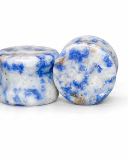Two polished blue and white marbled stone plugs standing upright on a white background.