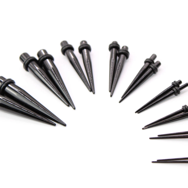 A complete ear stretching kit displayed in size order, featuring black acrylic tapers and matching double flare plugs. The tapers are sleek and lightweight, gradually increasing in size from 14G to 00G, designed to assist with smooth and safe ear stretching. Each size comes with a pair of straight tapers and a matching pair of plugs, all with rounded edges and rubber O-rings for secure placement. The set is neatly arranged to show the full gauge progression, ideal for beginne