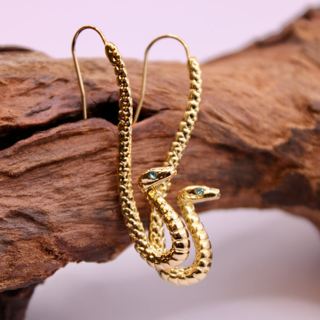 Embrace transformation and power with these Gold Serpent Earrings, featuring a sleek coiled snake design and piercing blue eyes that captivate. Snakes are ancient symbols of rebirth, protection, and hidden wisdom—making this pair a powerful accessory with deeper meaning.