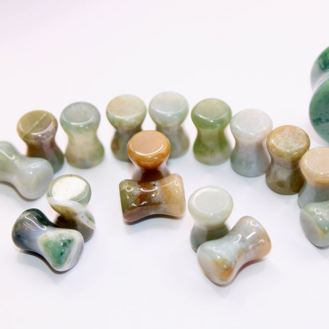 A beautifully varied pair of Rainbow Indian Agate Plugs rests on a natural-toned background, each plug showcasing its own unique mix of earthy colors. From deep forest green and mossy olive to warm rust, cream, and occasional hints of burgundy or gray, the natural banding and marbling of the stone give these plugs a one-of-a-kind character. The polished surface brings out the rich tones and subtle textures of the agate. Shaped with a comfortable, secure double flare, these plugs are perfect for those who ap