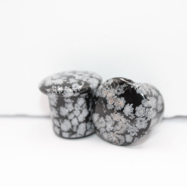 These Snowflake Obsidian Double Flared Plugs feature a smooth, polished surface with natural gray-white crystal "snowflakes" scattered across a rich black volcanic glass base. The double flare ensures a secure, comfortable fit for stretched ears without the need for O-rings. Each pair is uniquely patterned, showcasing the stone’s natural beauty and grounding energy. Durable and stylish, these plugs add a bold yet refined touch to any stretched ear jewelry collection.