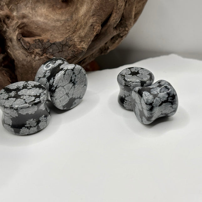 These Snowflake Obsidian Double Flared Plugs feature a smooth, polished surface with natural gray-white crystal "snowflakes" scattered across a rich black volcanic glass base. The double flare ensures a secure, comfortable fit for stretched ears without the need for O-rings. Each pair is uniquely patterned, showcasing the stone’s natural beauty and grounding energy. Durable and stylish, these plugs add a bold yet refined touch to any stretched ear jewelry collection.
