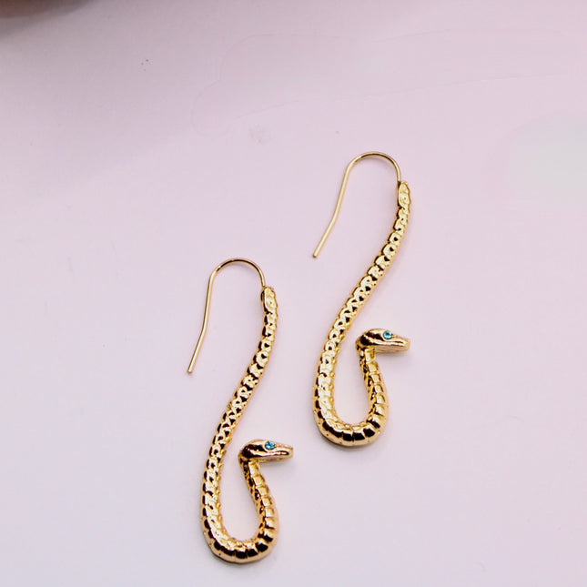 Embrace transformation and power with these Gold Serpent Earrings, featuring a sleek coiled snake design and piercing blue eyes that captivate. Snakes are ancient symbols of rebirth, protection, and hidden wisdom—making this pair a powerful accessory with deeper meaning.
